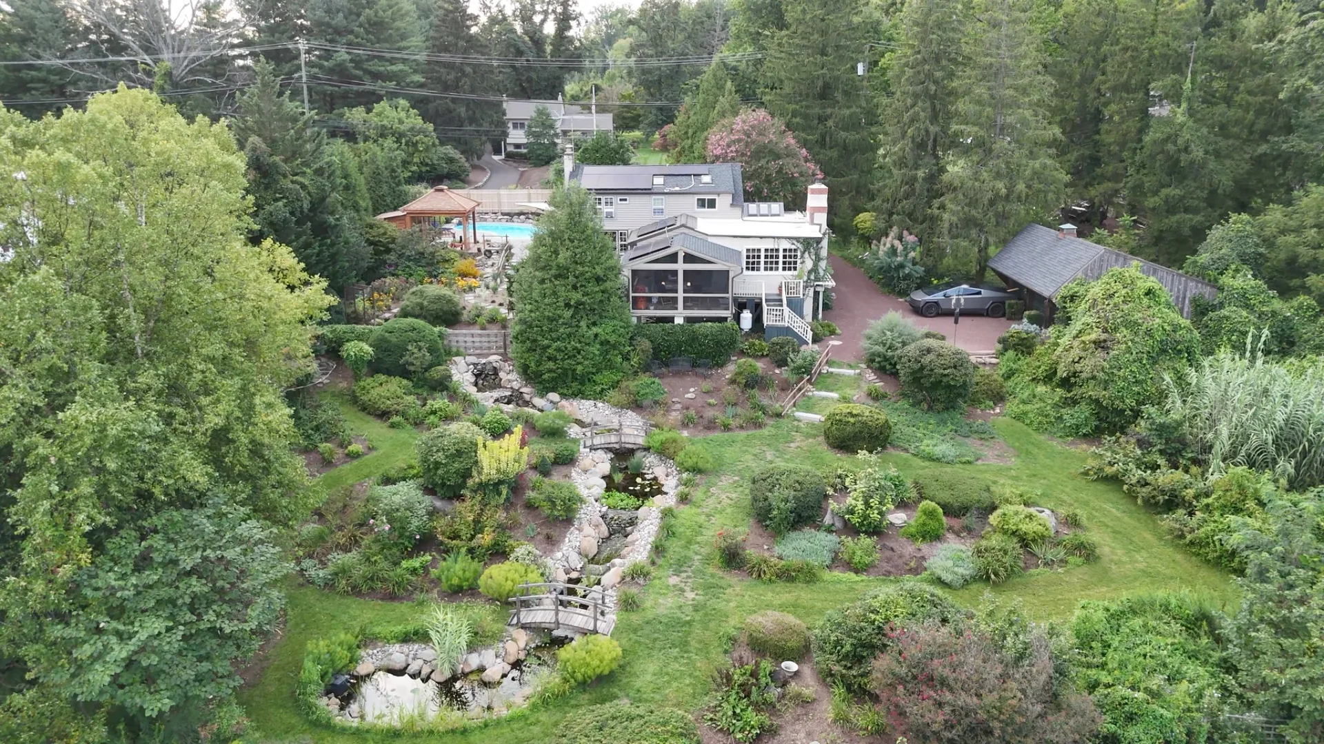 Aerial view of a real landscaped residential property with house, gardens and pool
